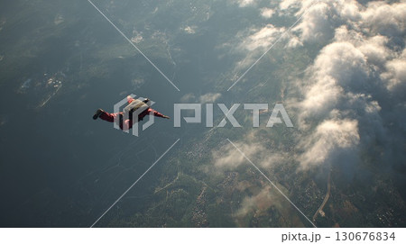 Skydiver is flying over landscape with clouds and mountains 130676834