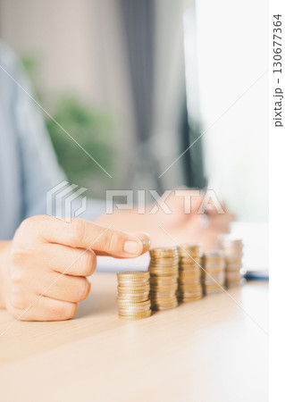 Hand places coin into saving jar, representing how smart finance, investment, banking practices turn money, cash, currency into financial wealth drives business growth and strengthens the economy. Hand places coin into saving jar, representing how smart finance, investment, banking practices turn money, cash, currency into financial wealth drives business growth and strengthens the economy. 130677364