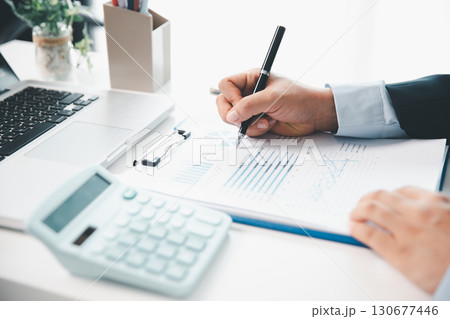 Accountant working on desk using calculator for calculate finance report in office. business finance, calculate tax by organizing financial documents, tracking income investment, accounting by hand. 130677446