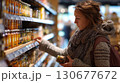Young woman choosing jar of pickled vegetables in supermarket 130677672