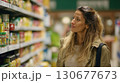 Young woman choosing jar of pickled vegetables in supermarket 130677673