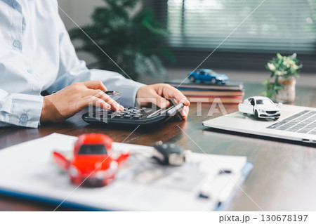 Dealership service desk, professional car salesman assists client with sale, finance documents for vehicle, ensuring smooth business transaction in retail transportation sector through signed contract Dealership service desk, professional car salesman assists client with sale, finance documents for vehicle, ensuring smooth business transaction in retail transportation sector through signed contract 130678197