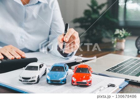 Businesswoman signing car insurance document or lease paper. Writing signature on contract or agreement. Buying or selling new or used vehicle. Car keys on table. Warranty or guarantee. 130678486