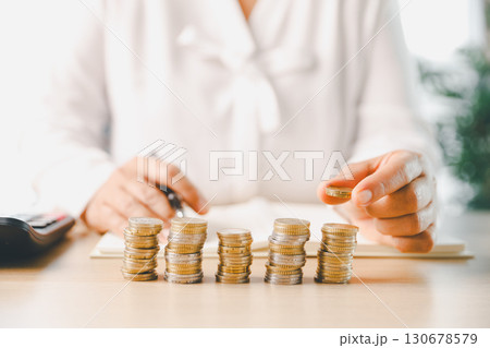 Hand places coin into saving jar, representing how smart finance, investment, banking practices turn money, cash, currency into financial wealth drives business growth and strengthens the economy. Hand places coin into saving jar, representing how smart finance, investment, banking practices turn money, cash, currency into financial wealth drives business growth and strengthens the economy. 130678579