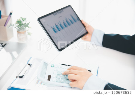 Accountant working on desk using calculator for calculate finance report in office. business finance, calculate tax by organizing financial documents, tracking income investment, accounting by hand. 130678653
