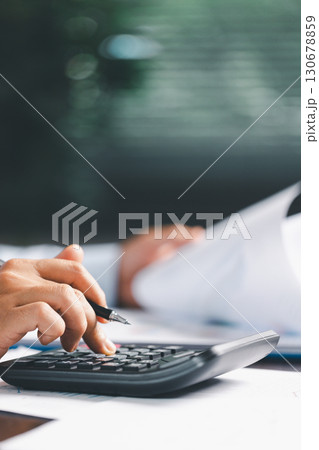 Businesswoman at table, calculator, monthly tax calculations, budgeting, managing expenses-illustrating business, finance, accounting, banking concept essential for effective budget management. Businesswoman at table, calculator, monthly tax calculations, budgeting, managing expenses-illustrating business, finance, accounting, banking concept essential for effective budget management. 130678859