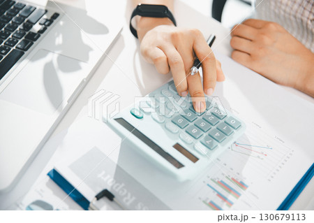 Accountant working on desk using calculator for calculate finance report in office. business finance, calculate tax by organizing financial documents, tracking income investment, accounting by hand. Accountant working on desk using calculator for calculate finance report in office. business finance, calculate tax by organizing financial documents, tracking income investment, accounting by hand. 130679113