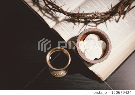 Communion bread and wine with the Holy Bible and crown of thorns, symbolizing the sacrifice of Jesus Christ, the passion, salvation and Christian faith in the Eucharist and Lord Supper. 130679424