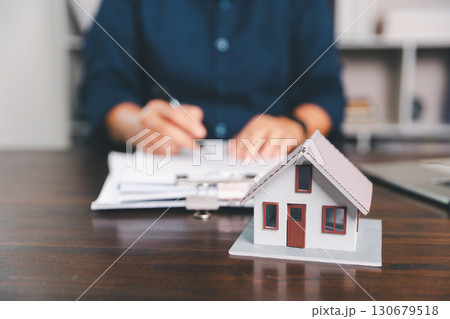 House model placed on table alongside coins, paperwork symbolizes real estate investment, property valuation, representing financial planning, mortgage options, market analysis in property business. House model placed on table alongside coins, paperwork symbolizes real estate investment, property valuation, representing financial planning, mortgage options, market analysis in property business. 130679518