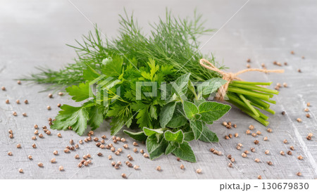 Fresh bundle of parsley, dill, and oregano with scattered coriander seeds on gray stone background, natural cooking ingredients. 130679830
