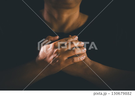 Hands clasped in prayer over the holy Bible, the faithful Christian worships God in church, holding onto hope and belief, guided by religion and a deep commitment to their religious faith. Hands clasped in prayer over the holy Bible, the faithful Christian worships God in church, holding onto hope and belief, guided by religion and a deep commitment to their religious faith. 130679882