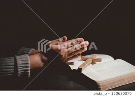 Hands folded in prayer on the Holy Bible, symbolizing faith, devotion, Christianity, hope, and spiritual strength. Concept of worship, meditation and trusting God Word. 130680070