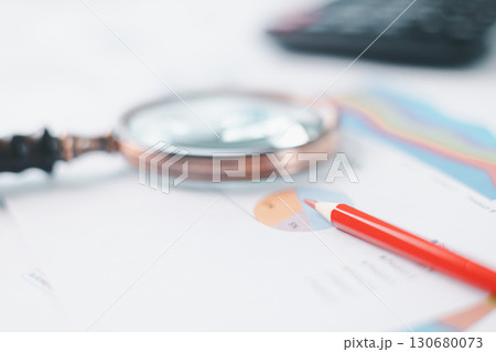 Magnifying glass with calculator and pen on financial reports with charts, graphs at office desk. Concept of business analysis, accounting audit, financial accuracy, transparency, corporate strategy. 130680073