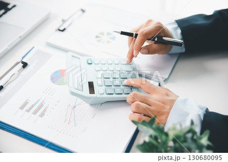 Accountant working on desk using calculator for calculate finance report in office. business finance, calculate tax by organizing financial documents, tracking income investment, accounting by hand. Accountant working on desk using calculator for calculate finance report in office. business finance, calculate tax by organizing financial documents, tracking income investment, accounting by hand. 130680095