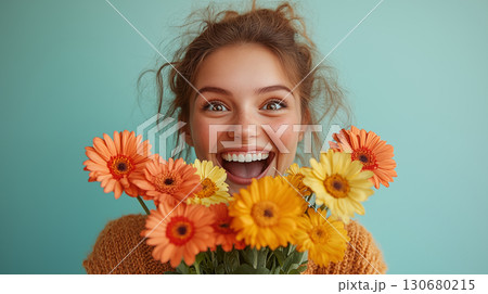 Woman smiling with gerbera daisies bouquet against turquoise background, expressing joy and happiness for spring celebration concept 130680215