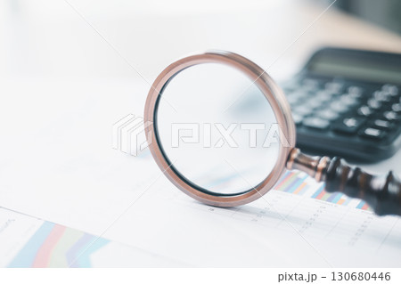 Magnifying glass with calculator and pen on financial reports with charts, graphs at office desk. Concept of business analysis, accounting audit, financial accuracy, transparency, corporate strategy. Magnifying glass with calculator and pen on financial reports with charts, graphs at office desk. Concept of business analysis, accounting audit, financial accuracy, transparency, corporate strategy. 130680446
