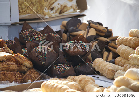 An enticing assortment of muffins, biscuits, and cream rolls are piled high at a bakery stand. An enticing assortment of muffins, biscuits, and cream rolls are piled high at a bakery stand. 130681686