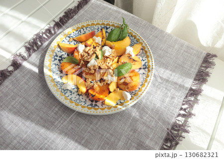 Fruit salad with cheese and honey on porcelain plate with blue pattern. Baked fruits. Food and vitamins, healthy eating. Seasonal products. 130682321