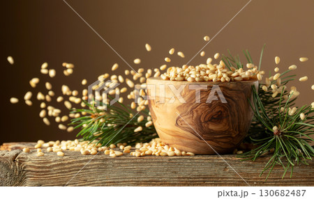 Flying peeled pine nuts on a brown background. 130682487