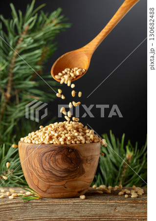 Pine nuts is poured in a wooden bowl. 130682488