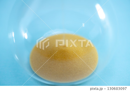 Telling time with an hourglass with sand flowing within a distance. Transparent hourglass. 130683097