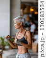 Fit senior woman in sportswear practicing boxing indoors, wearing fingerless gloves and a focused expression, standing in a light-filled modern space Fit senior woman in sportswear practicing boxing indoors, wearing fingerless gloves and a focused expression, standing in a light-filled modern space 130683534