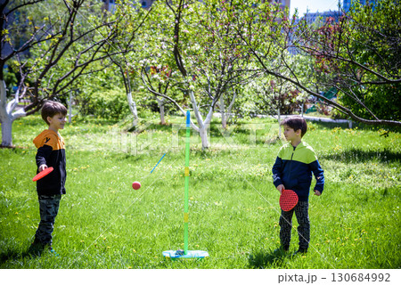 Two friends are playing tetherball swing ball game in summer camping. Two boy brother happy leisure healthy active time outdoors concept 130684992
