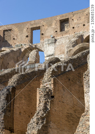 Rome, Italy - August 17, 2019: Fragment of the wall of the Colosseum - amphitheater, architectural monument of Ancient Rome. Rome, Italy - August 17, 2019: Fragment of the wall of the Colosseum - amphitheater, architectural monument of Ancient Rome. 130685139