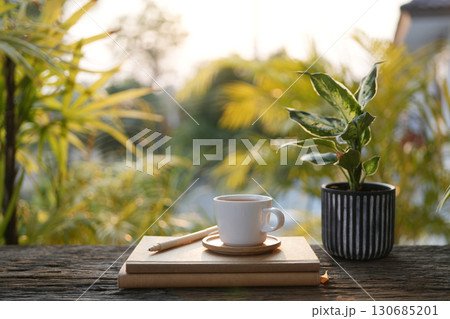 White coffee cup and notebook and potted plant outdoor cozy working space 130685201