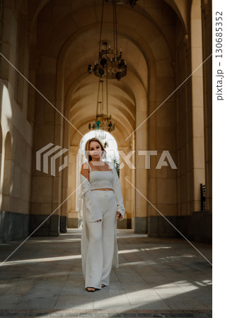 Woman White Outfit Architecture Hallway - A woman in a white outfit stands in a grand hallway of an architectural building. Woman White Outfit Architecture Hallway - A woman in a white outfit stands in a grand hallway of an architectural building. 130685352