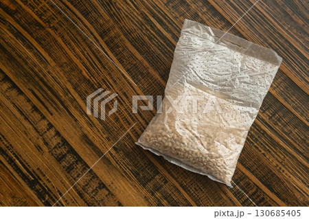 Pearl barley sachet for cooking on wooden kitchen table at home 130685405