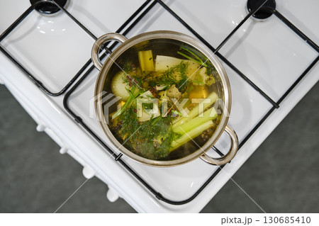 Boiling fresh vegetables in a pot on a stove in a modern kitchen setting Boiling fresh vegetables in a pot on a stove in a modern kitchen setting 130685410