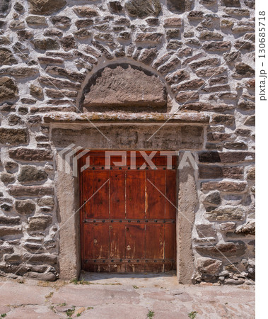 Historic Stone Wall with Arched Wooden Door 130685718