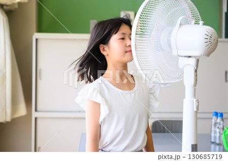 扇風機の風にあたる小学生の女の子 夏の涼しさと暮らしのイメージ 扇風機の風にあたる小学生の女の子 夏の涼しさと暮らしのイメージ 130685719