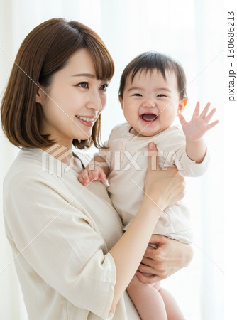 笑顔で赤ちゃんを抱っこする母親と幸せな親子の時間 130686213