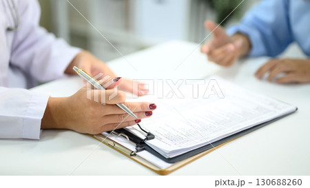 Physician filling out medical forms while listening to a patient in a clinical. Health care concept Physician filling out medical forms while listening to a patient in a clinical. Health care concept 130688260