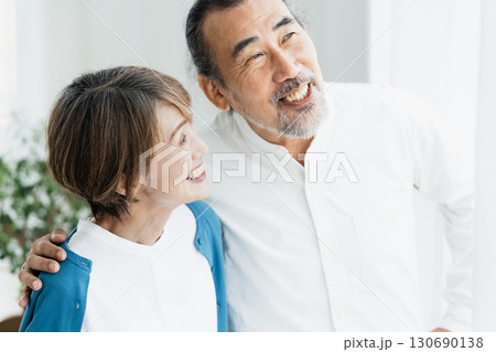 窓際で外を見るシニア夫婦 130690138