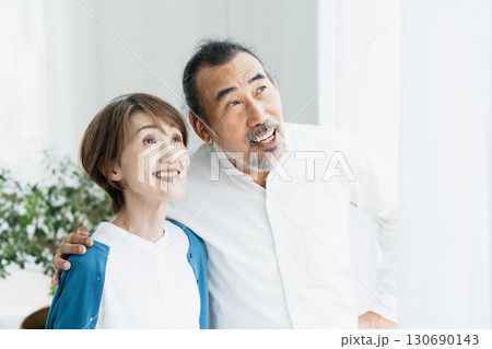 窓際で外を見るシニア夫婦 130690143