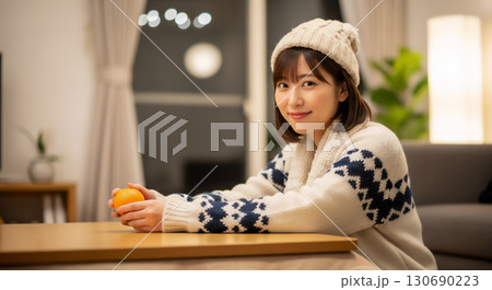 こたつでみかんを食べる女性のポートレート 130690223
