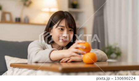 こたつでみかんを食べる女性のポートレート 130690224