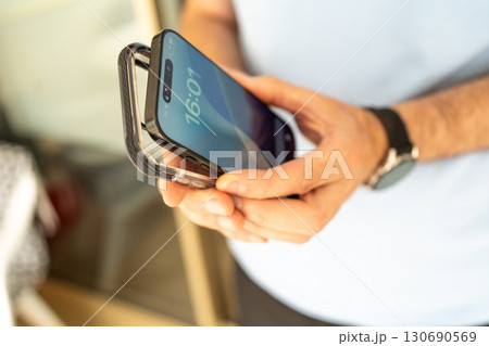 Close-up of a man holding a smartphone and a transparent protective case, preparing to put the case on the phone. Close-up of a man holding a smartphone and a transparent protective case, preparing to put the case on the phone. 130690569