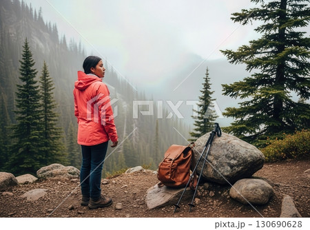 Solo Hiker Gazing at a Mountain Valley View from a Misty Pine Forest Trail 130690628