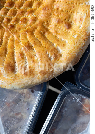 Traditional hot Uzbek bread close-up, fresh baked round flatbread with golden crust Traditional hot Uzbek bread close-up, fresh baked round flatbread with golden crust 130690692