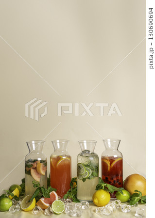 Assortment of lemonades in pitchers with ice on peach background 130690694