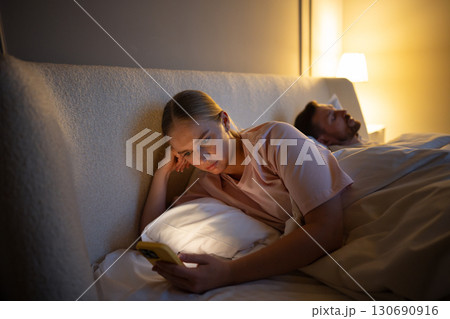 Tired woman awake absorbed in social media in phone, insomnia worsens, digital addicton, cheating Tired woman awake absorbed in social media in phone, insomnia worsens, digital addicton, cheating 130690916
