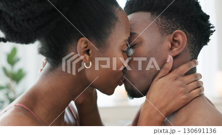 Couple, kiss and intimate in bedroom, closeup and love in passion, sex and romance by seduction. Black people, marriage and sexy on honeymoon, natural and desire in erotic or bonding for relationship 130691136