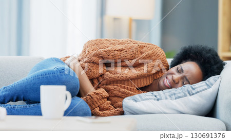 Stomach pain, pms and black woman on a sofa with anxiety, gas or endometriosis at home. Menstruation, constipation and African female with period crisis, stress or digestion problem in a living room Stomach pain, pms and black woman on a sofa with anxiety, gas or endometriosis at home. Menstruation, constipation and African female with period crisis, stress or digestion problem in a living room 130691376
