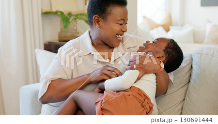 Mother, happy and child on a couch, home and funny with happiness, playing and weekend break. Black family, mama and baby on a sofa, fun and relax with humor in a living room, tickle and smile 130691444