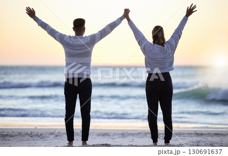 Couple at beach with hands up, freedom and travel, ocean waves and view, love and adventure together. Relationship, carefree and peace with man and woman with arms in air, back and sunrise in Bali Couple at beach with hands up, freedom and travel, ocean waves and view, love and adventure together. Relationship, carefree and peace with man and woman with arms in air, back and sunrise in Bali 130691637