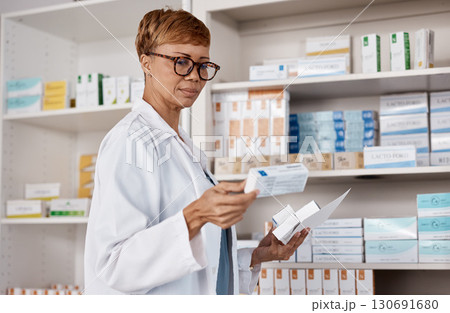 Pharmacist, medicine and healthcare with a woman working and reading information on pills box. Black person in a pharmacy, clinic or shop for pharmaceutical, medical and health service or inventory Pharmacist, medicine and healthcare with a woman working and reading information on pills box. Black person in a pharmacy, clinic or shop for pharmaceutical, medical and health service or inventory 130691680